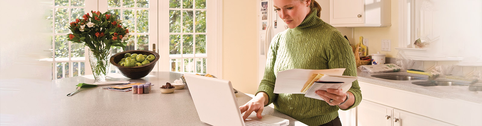 Woman in kitchen on laptop